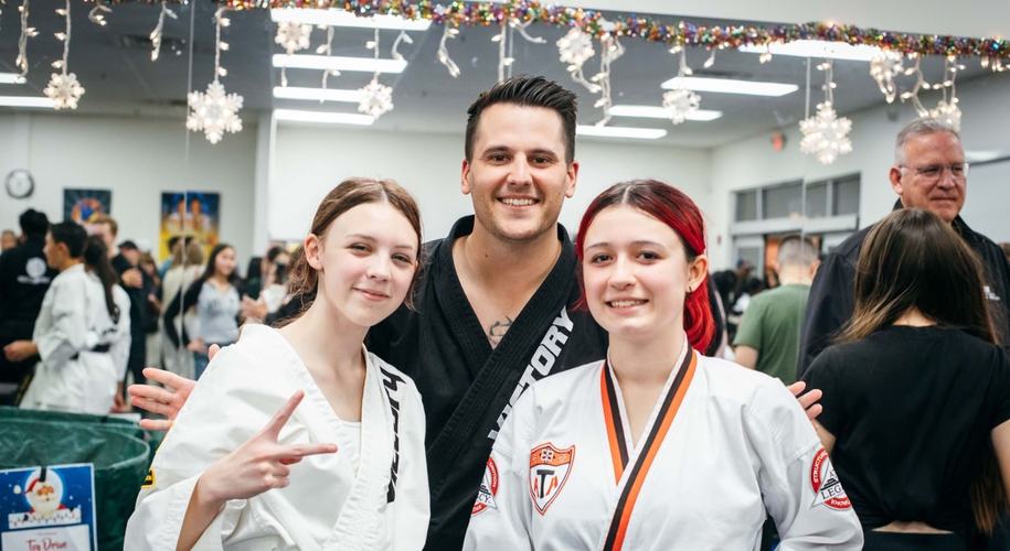Two teen students smile with their instructor at a holiday event